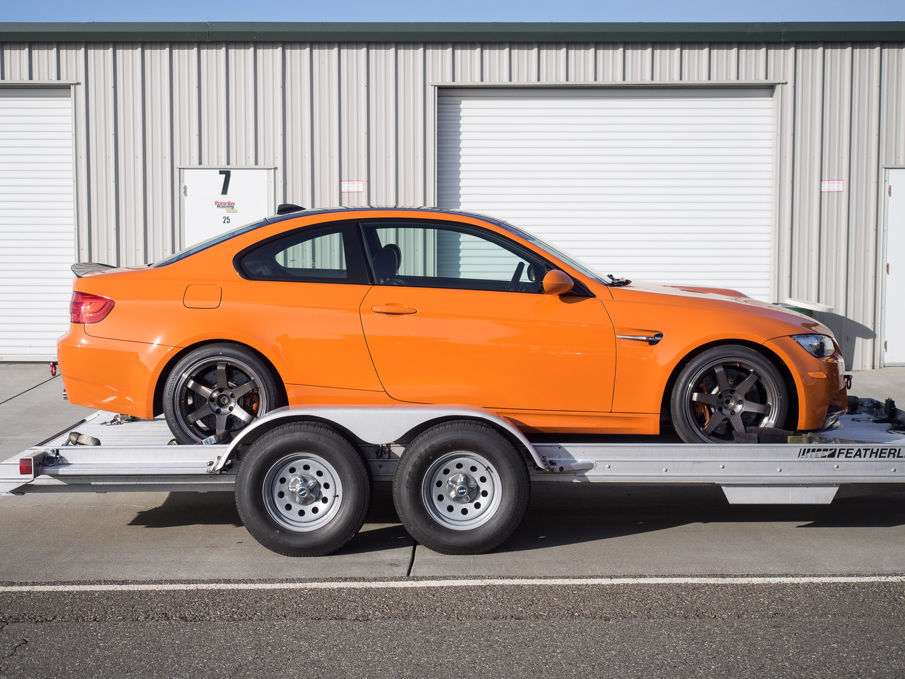 Bright orange sports car on a trailer. Photo directly from the side.