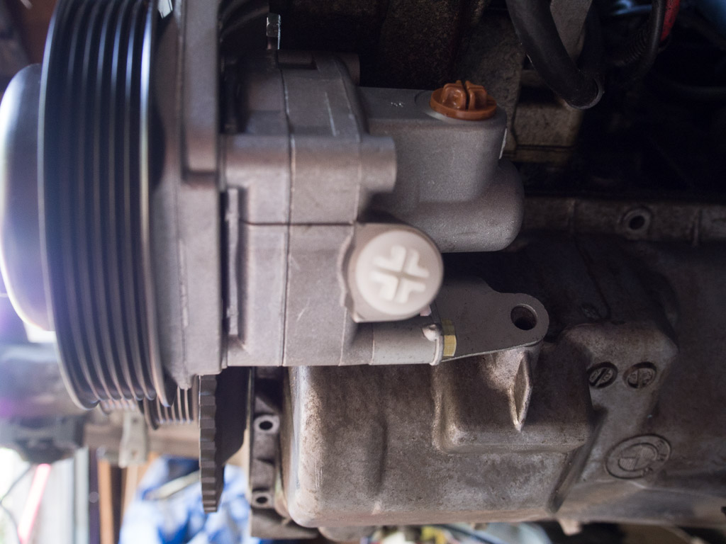 The M3 power steering pump has rear ear which reaches backwards and bolts to the oil pan.