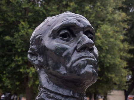 Bronze bust, photo taken several feet away with a normal or 'telephoto' lens. The bust takes up most of the frame and the background is minimized.