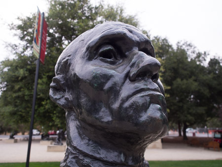 Bronze bust, photo taken just a few inches away with a wide angle lens. The bust takes up most of the frame. There is a lot of background environment present.